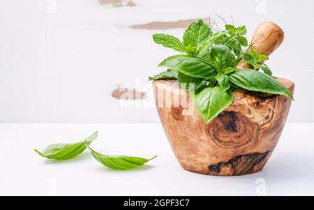 Medicina alternativa le erbe fresche nel mortaio di legno . Gli ingredienti alimentari e condimento basilico, menta piperita , aneto e menta verde in un mortaio di legno insieme Foto Stock