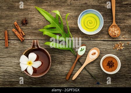 Gli avocadi lascia con la natura spa ingredienti essiccati bael indiana ,cannella in polvere ,bastoncini di cannella ,olio aromatico ,anice stellato e sale marino su rustiche bac Foto Stock