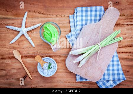 Alternative di cura per la pelle e scrub. Natural spa ingredienti citronella e sale marino impostato su sfondo di legno. Foto Stock