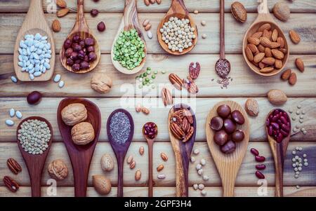 Legumi vari e diversi tipi di nutshells in cucchiai. I kernel di noci, nocciole, mandorle ,brown pinto ,i fagioli di soia ,semi di lino ,chia ,cece ,ri Foto Stock