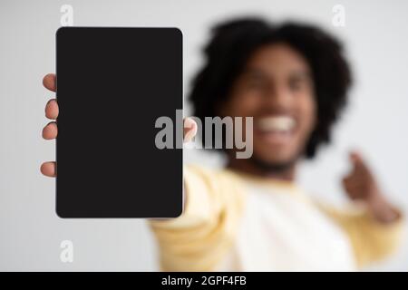 Allegro ragazzo nero che mostra e indica il tablet digitale con schermo vuoto Foto Stock