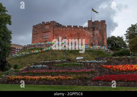 Il Castello di Tamworth si erge sopra i bellissimi aiuole fiorite nei giardini circostanti, visti prima della caduta notturna nel settembre 2021. Foto Stock