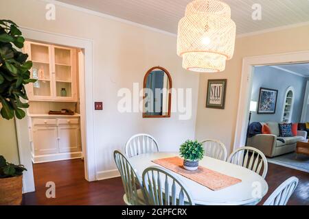 Una piccola sala da pranzo con un'illuminazione in rattan di tendenza e un tavolo da pranzo dipinto di blu Foto Stock