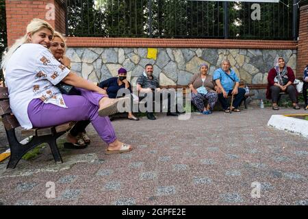 Beyoglu, Istanbul, Turchia - 06.27.2021: Un gruppo di allegri cittadini turchi zingari si siede su diverse panchine pubbliche e guardando la macchina fotografica e posin Foto Stock