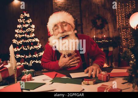 Foto ritratto allegro sorridente santa indossare occhiali headwear maglione ridendo preparare regali per Natale Foto Stock