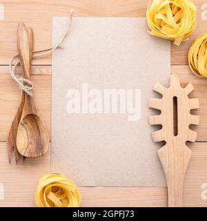 Cibi italiani del concetto e del design del menu . Carta bianca e pasta siviera su sfondo di legno. Foto Stock