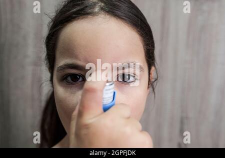 Bambina che usa spray medico per il respiro. Inalatore. Vista frontale Foto Stock