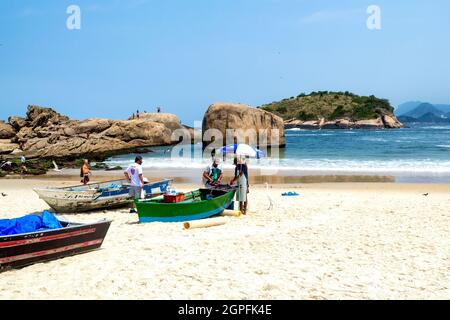Le barche artigianali da pesca sono viste nella sabbia della spiaggia di Piratininga a Nitreoi, Rio de Janeiro, Brasile. I brasiliani sono visti nella scena che Foto Stock