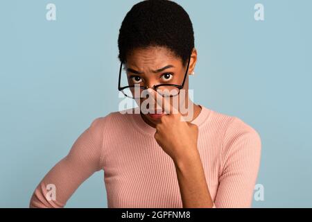 Che cosa hai detto. Black Woman regolare gli occhiali e guardare la fotocamera Foto Stock