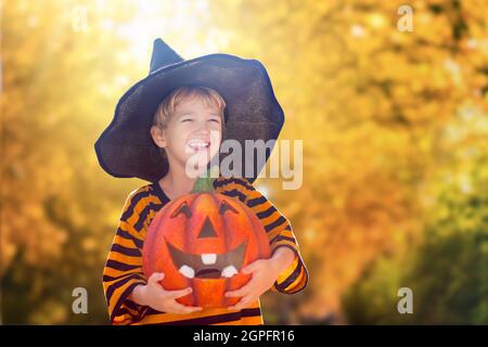 I bambini trick o trattare in costume di Halloween. I bambini in coloratissima vesti con secchio di caramelle sulla strada suburbana. Il ragazzino e la ragazza trick o trattare Foto Stock