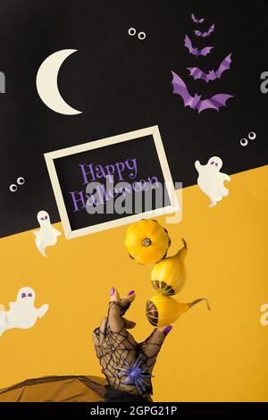 Composizione astratta di Halloween in giallo, viola, nero, bianco. Texte sur Happy Halloween sulla lavagna. Sagome di carta di pipistrelli, fantasmi, occhi. Mano Foto Stock