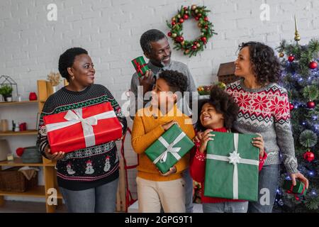 felice famiglia afroamericana con regali di natale che si guardano a casa Foto Stock