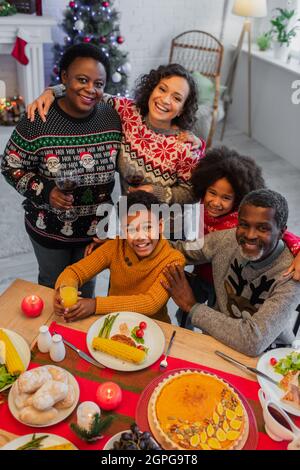 vista ad alto angolo della gioiosa famiglia afroamericana che guarda la macchina fotografica durante la cena di natale Foto Stock