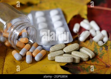 Pillole su foglie di acero giallo, flacone di capsule e blister di compresse. Concetto di integratori alimentari, antidepressivi, vitamine Foto Stock