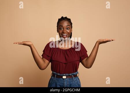 Donna afro-americana confuso che tiene qualcosa di invisibile su entrambe le palme Foto Stock