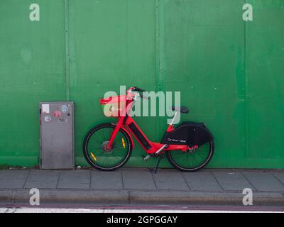 On Lime + Uber noleggio bici a Battersea Londra, parcheggiata accanto al muro verde Foto Stock