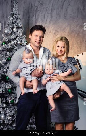 Una famiglia grande felice con i bambini gemelli nell'interno di Capodanno della casa sullo sfondo di un albero di Natale. Foto Stock