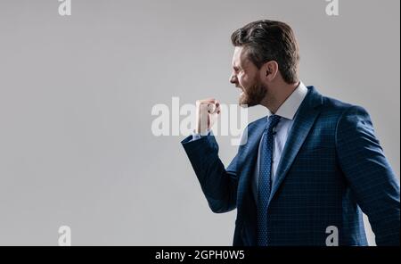 Uomo d'affari aggressivo in tuta minacciare il gesto scuotendo pugno a qualcuno, minacciando Foto Stock