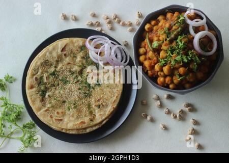 Perfettamente rotonda Paratha. Pane piatto indiano fatto di farina di grano con semi di sesamo e foglie di coriandolo servito con salsa di ceci bianca comunemente Foto Stock
