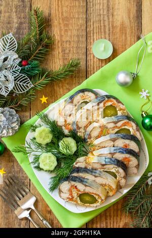 Spuntino festivo. Rotolo di sgombro al forno ripieno di formaggio, carote, uova e cetriolo sottaceto, servito al tavolo di Natale. Vista dall'alto, backgroun piatto Foto Stock