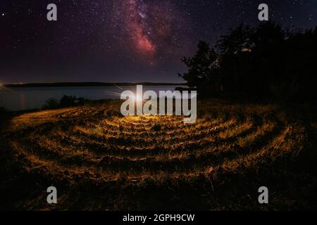 Labirinto a spirale fatto di pietre sulla costa nella notte stellata Foto Stock