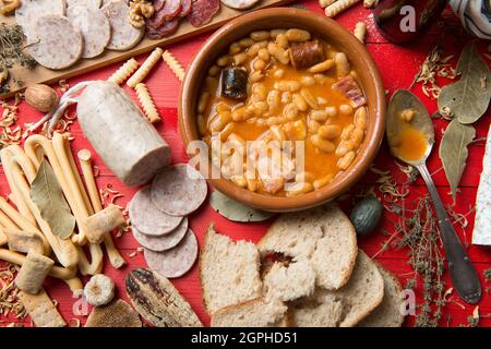 Piatto di fagioli asturiani su un tavolo pieno di cibo Foto Stock