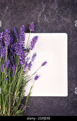 Mockup di blocco note vuoto aperto con bouquet di lavanda su sfondo di pietra nera, spazio di copia per il testo Foto Stock