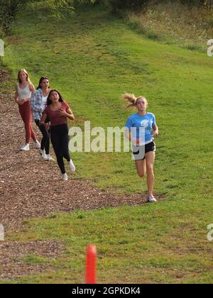 La vostra ragazza teen che gareggia e vince un incontro locale di cross-country della scuola media in New Jersey, Stati Uniti d'America ed essendo incoraggiata da parecchi amici lungo il percorso Foto Stock