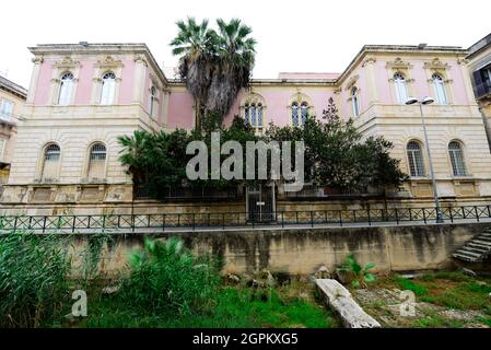 I ruderi della porta Ubica con il bell'antico edificio che funge da sede della Banca Monte dei Paschi di Siena a Ortigia, Siracusa. Foto Stock