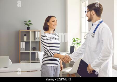 Donna matura felice scuotendo le mani con un medico amichevole in clinica o ospedale Foto Stock