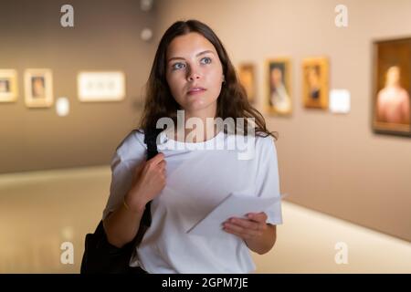 Ragazza focalizzata visitatore, ammira i dipinti nel museo Foto Stock