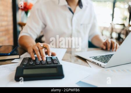 businessman mano che utilizza il calcolatore per calcolare circa costo, tasse o budget sul tavolo in ufficio. Foto Stock