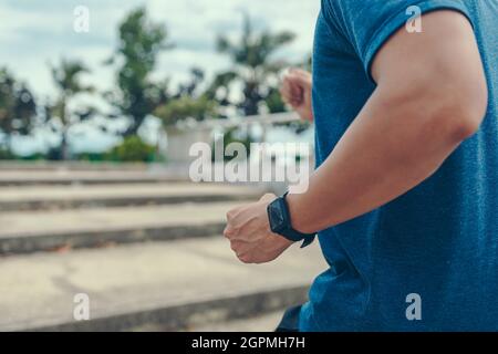 Un uomo che indossa un orologio intelligente con correre fino alla scala al tramonto. Foto Stock
