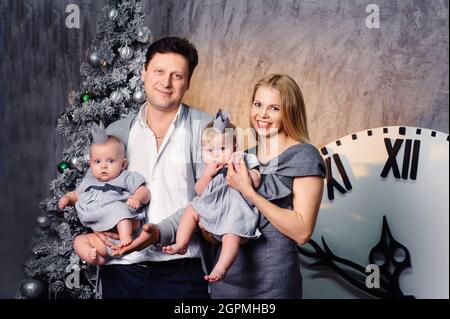 Una famiglia grande felice con i bambini gemelli nell'interno di Capodanno della casa sullo sfondo di un albero di Natale. Foto Stock