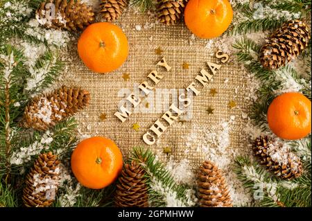 Natale e Capodanno sfondo nelle tradizioni russe della vacanza. Mandarini aranciati maturi, coni di abete rosso e rami innevati di abete rosso Foto Stock