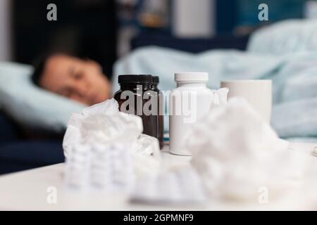 Primo piano di bottiglie e pillole per la donna malata con virus. Persona che prende la medicina essendo malsana, avendo sintomi di influenza fredda e febbre. Adulto su farmaco contro infezione e mal di testa. Foto Stock