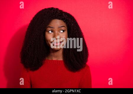 Foto di bella pelle scura signora indossare casual maglione sorridente guardando vuoto spazio isolato colore rosso sfondo Foto Stock