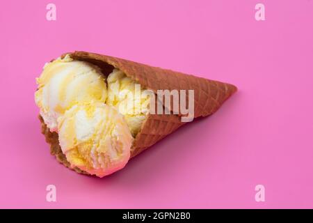 Palline di gelato profumate di frutta in un cono di waffle su sfondo rosa Foto Stock