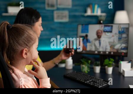 Famiglia che ha consulenza medica virtuale discutere di trattamento pillole con medico a distanza durante la conferenza on-line videocall riunione. Chiamata Telemedicine sullo schermo del computer in quarantena Foto Stock