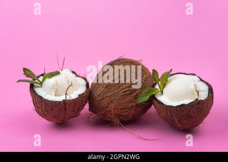 Palline di gelato alla vaniglia in semi di cocco fresco decorate con foglie di menta su sfondo rosa. Foto Stock