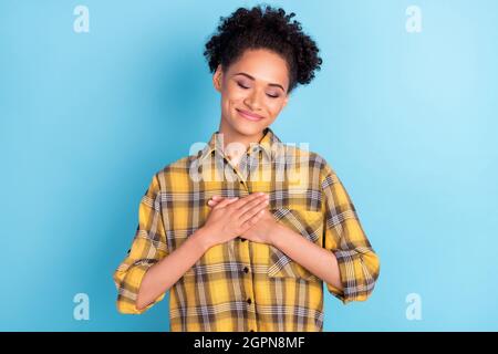 Foto ritratto curly donna mantenendo le mani sul petto grata sorridente sincero isolato pastello blu sfondo di colore Foto Stock