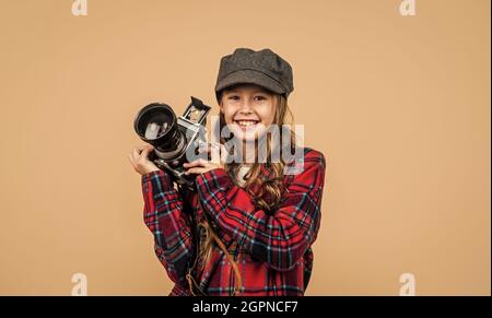 look retrò parigino. moda casual francese. fotografo ragazza felice in giacca a scacchi. bambino primavera con fotocamera. bambino con cappello alla moda Foto Stock