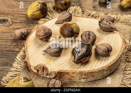 Juglans coriformis Maxim o noce a forma di cuore. Verde giovane e noci intere non pelate su un supporto. Sfondo vintage tavole di legno, primo piano Foto Stock