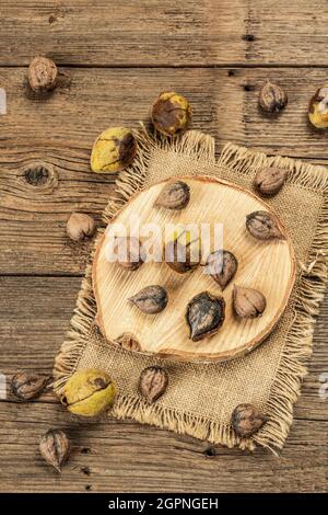 Juglans coriformis Maxim o noce a forma di cuore. Verde giovane e noci intere non pelate su un supporto. Vintage tavole di legno, vista dall'alto sfondo Foto Stock