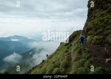 NEPAL - 31 MAGGIO 2016: Un uomo non identificato cammina sul sentiero stretto sul bordo della montagna sul percorso di trekking a Machapuchare Foto Stock