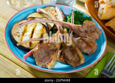 Arrosti di carni di montone nervature servito con melanzane al forno e le erbe aromatiche Foto Stock