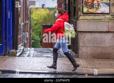 Donna che corre indossando maschera medica a Preston, Lancashire. UK Weather 30 settembre 2021; negozi, shopping in una giornata bagnata e ventosa nel centro della città. Credit : Mediaworld Images/AlamyLiveNews Foto Stock