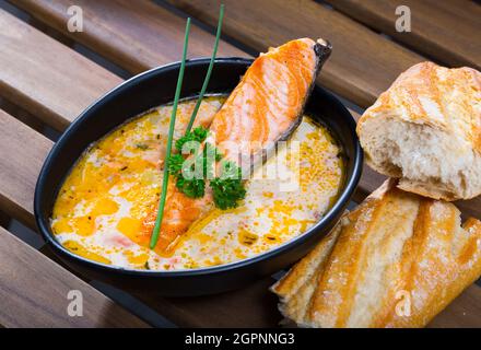 Deliziosa zuppa di salmone cremosa in ciotola nera servita con baguette Foto Stock