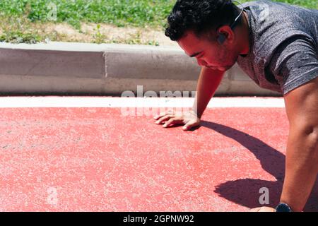 Uomo latino attivo che fa i push-up all'aperto Foto Stock