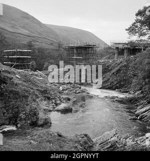 Una vista della costruzione dell'autostrada M6 attraverso la Gola di Lune, che mostra la costruzione di un ponte sul fiume Lune, probabilmente il ponte Roger Howe che porta la A685 attraverso il fiume. I lavori sulla sezione Lune Gorge dell'autostrada M6 tra Killington e Tebay (Junction 37 - Junction 38) sono stati eseguiti da John Laing Construction Ltd. I lavori sono iniziati nell'ottobre 1967 e l'autostrada è stata aperta al traffico nell'ottobre 1970. Su questo tratto della M6 sono stati costruiti 20 ponti e 17 colvert attraverso fiumi e ruscelli. Il ponte Roger Howe si trova presso la griglia di riferimento NY612960275 Foto Stock